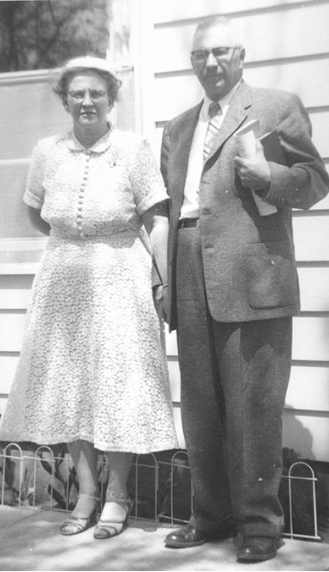 An old photo of a man and woman standing in front of a house.