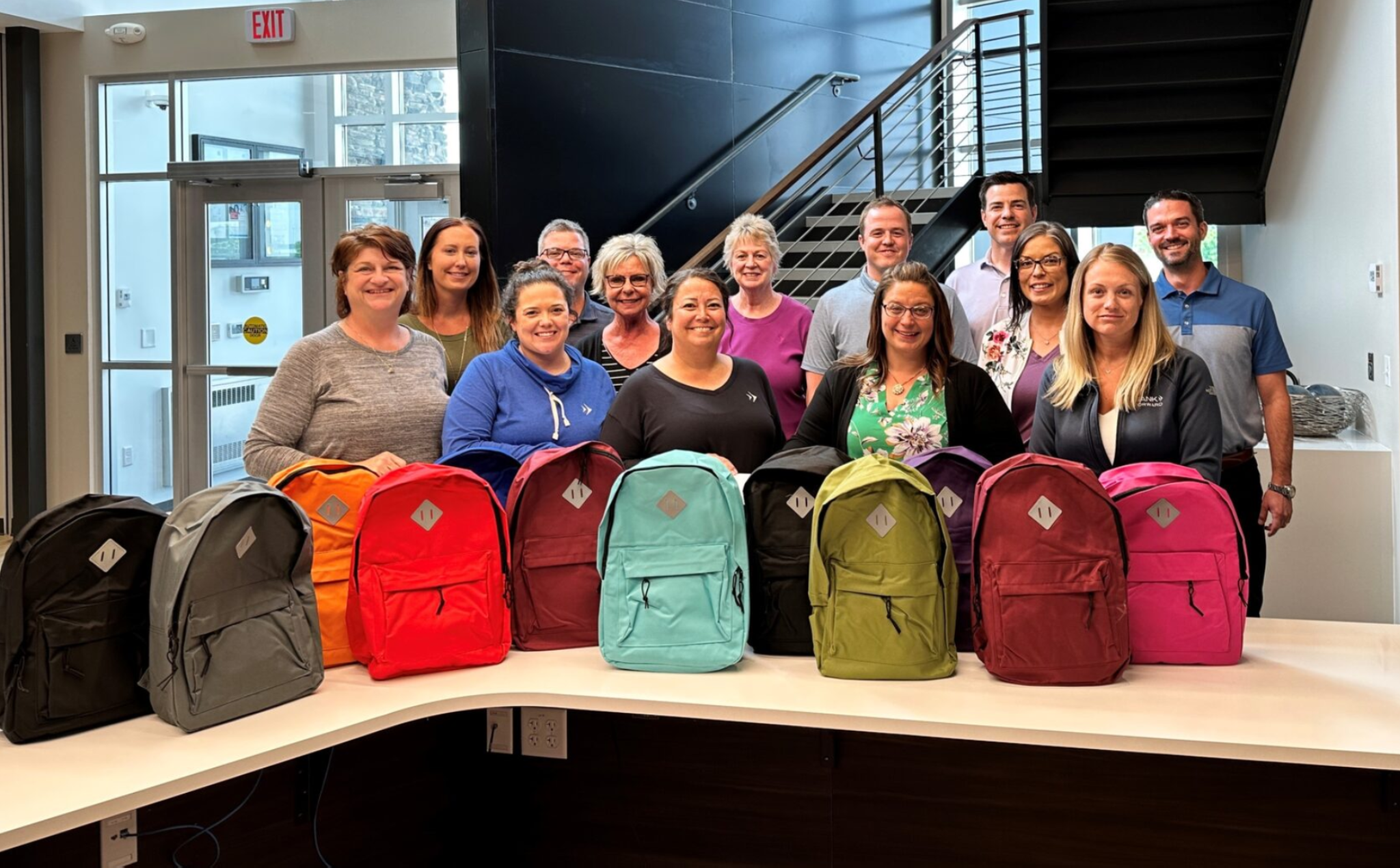 A group of people standing in front of a table full of backpacks.